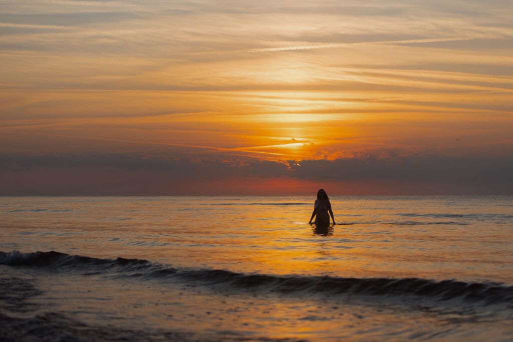 sesja nagości nad morzem o zachodzie słońca